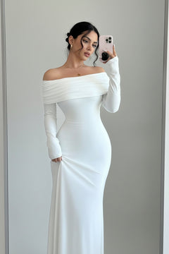 White off-shoulder long sleeve maxi dress with fitted sleeves and draped neckline.