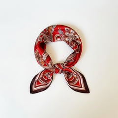 Deep red silk paisley scarf knotted at the center, showing white and brown swirls