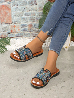 Open-toe flat sandals with blue patterned straps, brown outsole, and toe cutouts