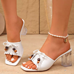 White open-toe block heel mules with tassel fringe, beaded charms, clear heel