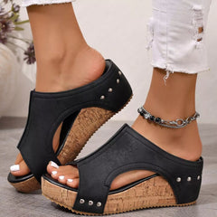 Black open-toe wedge sandals with side cutouts, stud details, and cork-look wedge