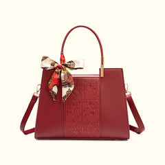 Red embossed leather top-handle handbag with front panel and bow scarf