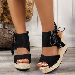 Black open-toe wedge sandal with lace-up ankle ties and tassel fringe
