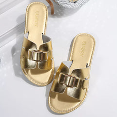 Gold open-toe slide sandals with wide strap and square buckle detail, flat sole.