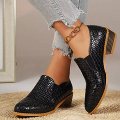 Point-toe block heel loafers in black, textured upper and gold chain ankle detail.