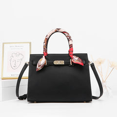Black leather handbag with detachable shoulder strap and patterned scarf top handles