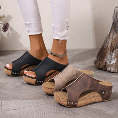 Black open-toe wedge sandals with cutout sides, stud accents, and cork-look sole