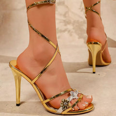 Gold open-toe stiletto sandals with gem flower toe strap and tall ankle wrap