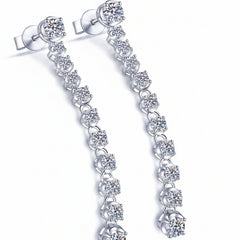 Silver drop earrings with prong-set round moissanite stones along a chain