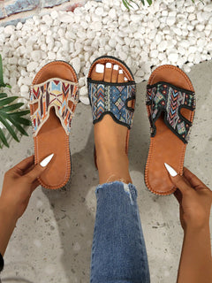 Three open-toe flat sandals with patterned straps and white toenail cutouts