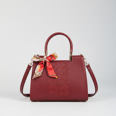 Red embossed leather top-handle handbag with side straps and bow scarf