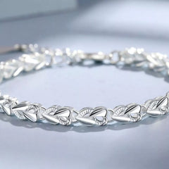 Silver heart link bracelet featuring engraved petal-style heart motifs