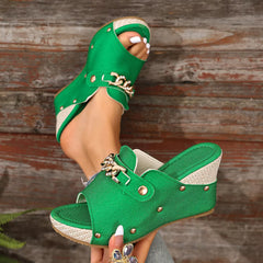 Green open-toe wedge sandals with chain buckle strap and metal stud trim.
