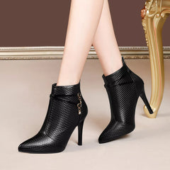 Black pointed-toe stiletto ankle boots with textured upper and side chain strap detail