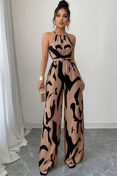 Sleeveless wide-leg jumpsuit with abstract tan-and-black print, halter neck and tied waist