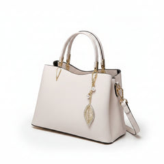 White leather top-handle handbag with dangling leaf charm and side strap