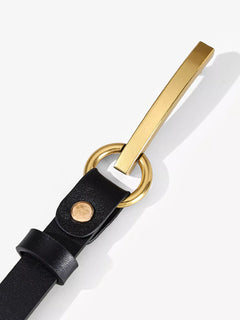 Close-up of black leather belt with gold buckle and round rivet detail