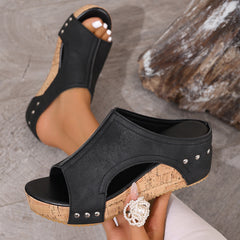 Black open-toe wedge sandals with stud trim and white flower charm, cork-look wedge