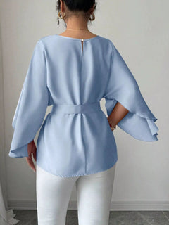 Light blue belted blouse with batwing sleeves and square buckle, back view