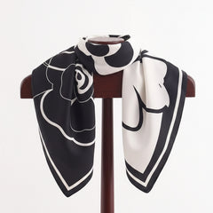 Square flower silk scarf draped on a stand, black and white floral motif
