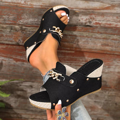Black open-toe wedge sandals with gold chain buckle and metal studs.