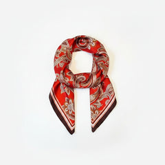 Deep red silk paisley scarf draped in a loop with white and brown swirl motifs