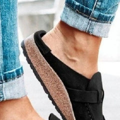 Black round-toe low-heel loafers with front buckle strap and tan textured sole