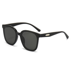 Oversized square sunglasses with black frames and dark lenses, gold bridge detail