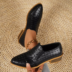 Point-toe block heel loafers in black with textured finish, gold chain detail.
