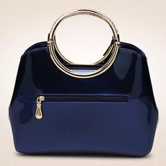 Indigo glossy handbag with round ring handle, front zip pocket, and gold accents