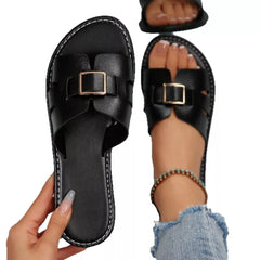 Black open-toe slide sandals, flat sole, wide strap with square buckle.