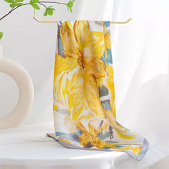 Silk square scarf tied in a bow on stand, yellow, white, and gray floral print