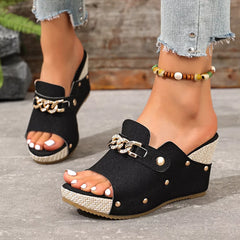 Black open-toe wedge sandals with chain-buckle strap and stud details.